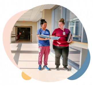 Two medical professionals stand in hallway looking at chart