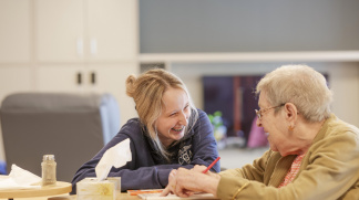 CCA worker sitting at a table with a senior