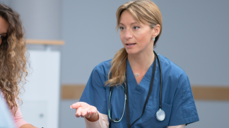 Nurse in blue scrubs speaking to patient just out of photo