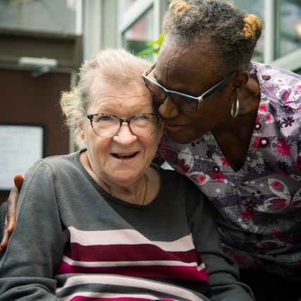 Continuing Care Worker in an embrace with elderly patient.