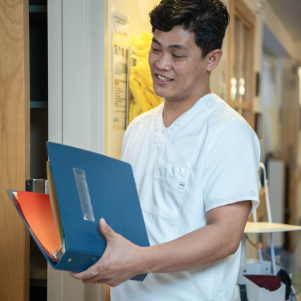Licensed practical nurse reviewing a chart in a hospital hallway