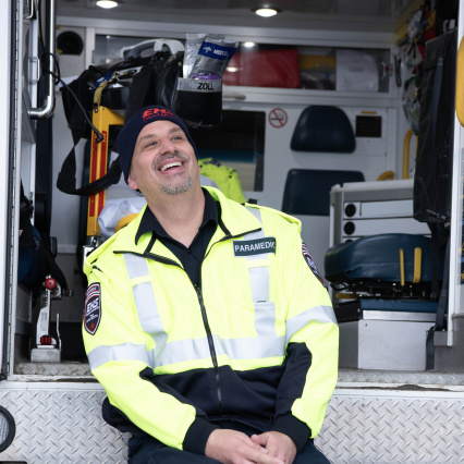 Paramedic smiling sitting on the back of an open ambulance